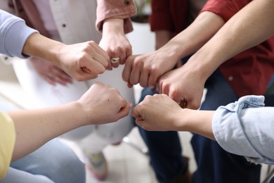 Photo of Unity concept. People holding fists together indoors, closeup