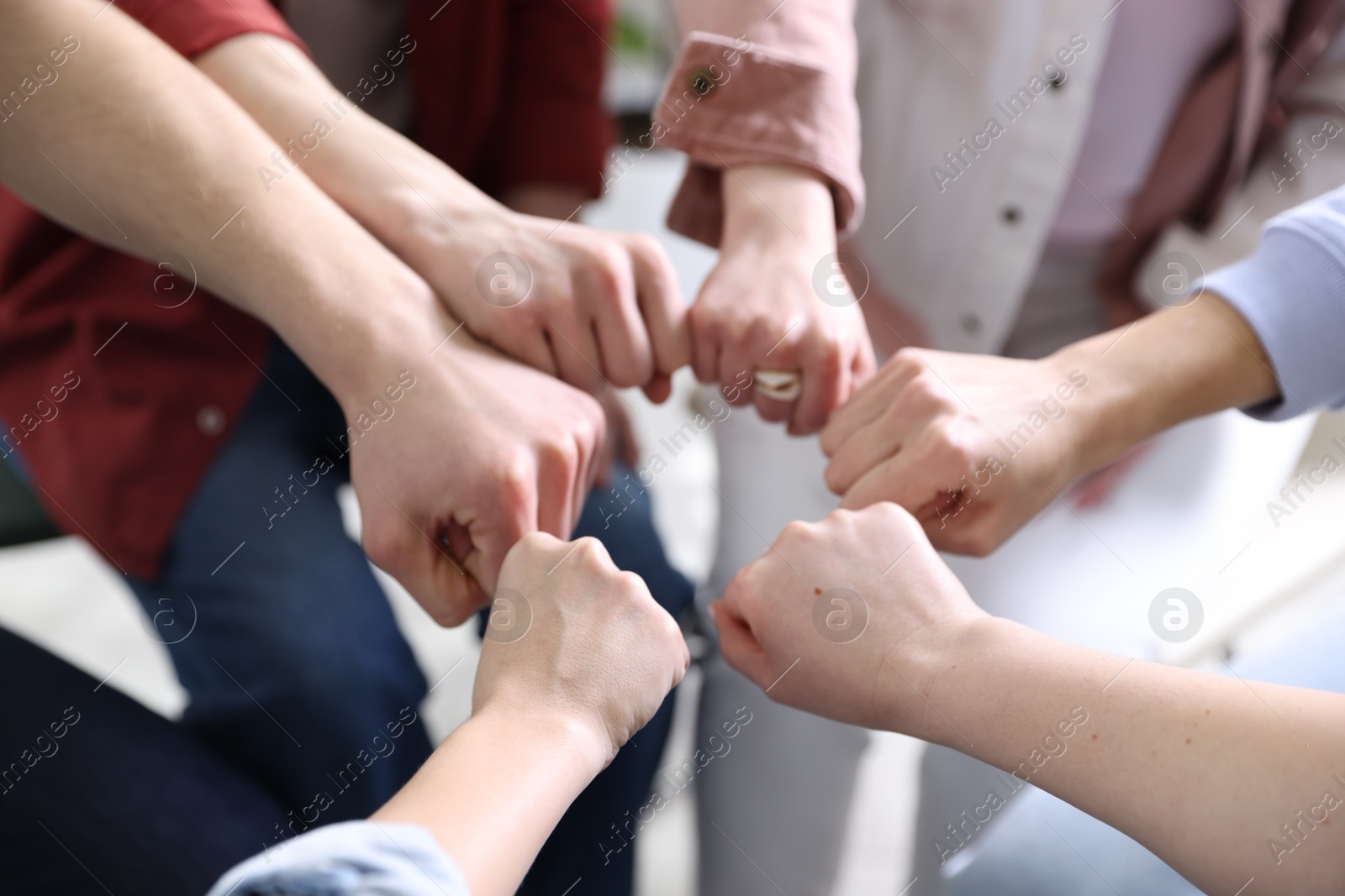 Photo of Unity concept. People holding fists together indoors, closeup