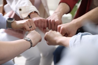 Photo of Unity concept. People holding fists together indoors, closeup