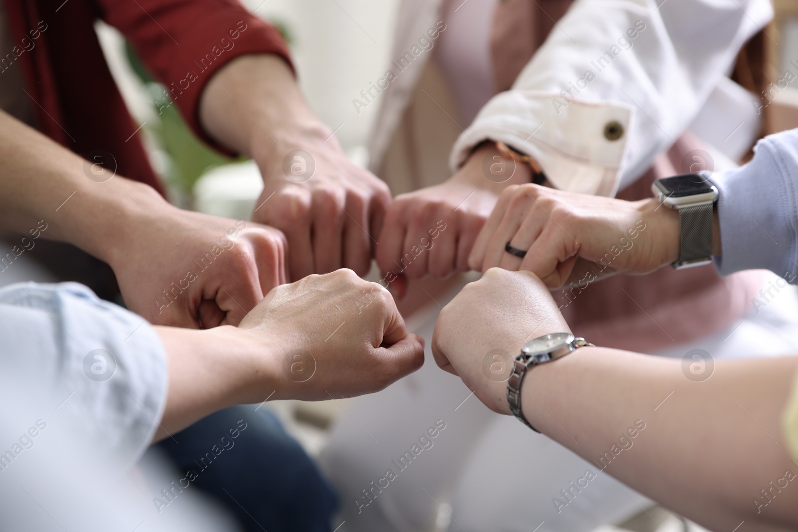 Photo of Unity concept. People holding fists together indoors, closeup