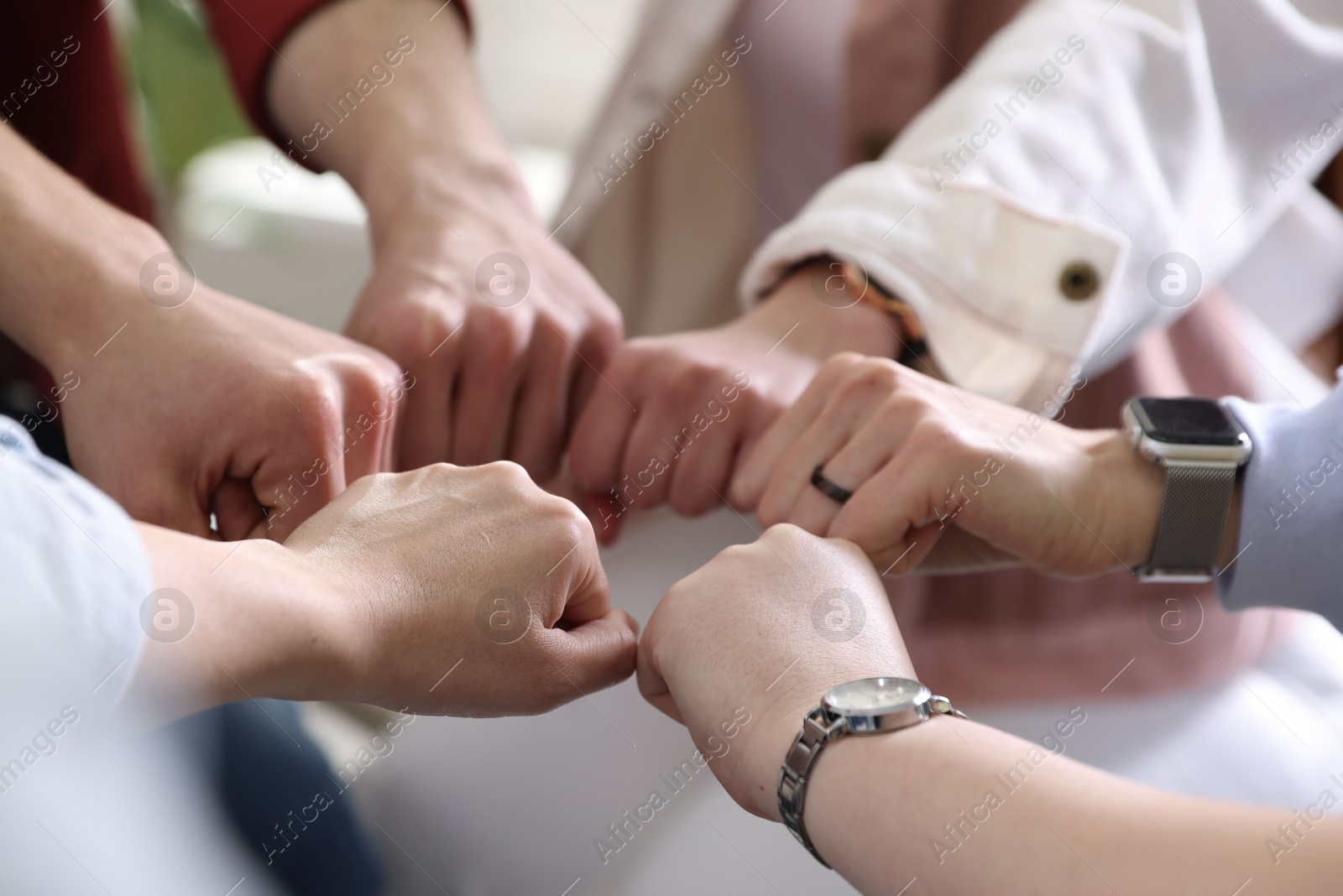 Photo of Unity concept. People holding fists together indoors, closeup