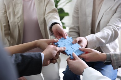 Photo of Unity concept. People putting puzzle pieces together indoors, closeup