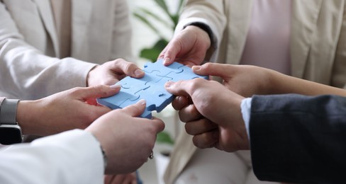 Photo of Unity concept. People putting puzzle pieces together indoors, closeup