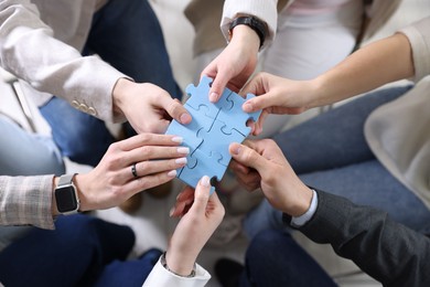 Photo of Unity concept. People putting puzzle pieces together indoors, top view