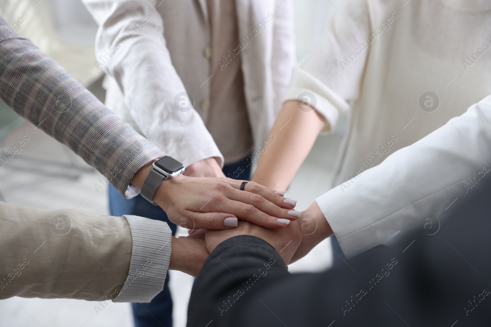 Photo of Unity concept. People holding hands together indoors, closeup