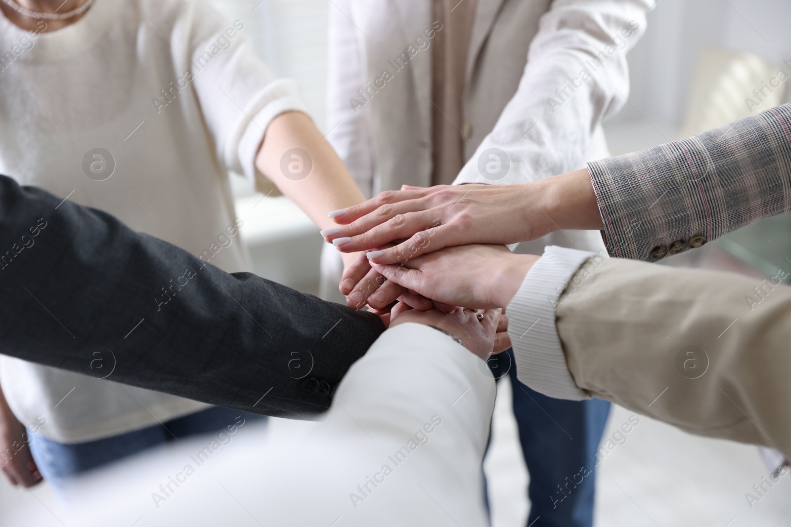 Photo of Unity concept. People holding hands together indoors, closeup