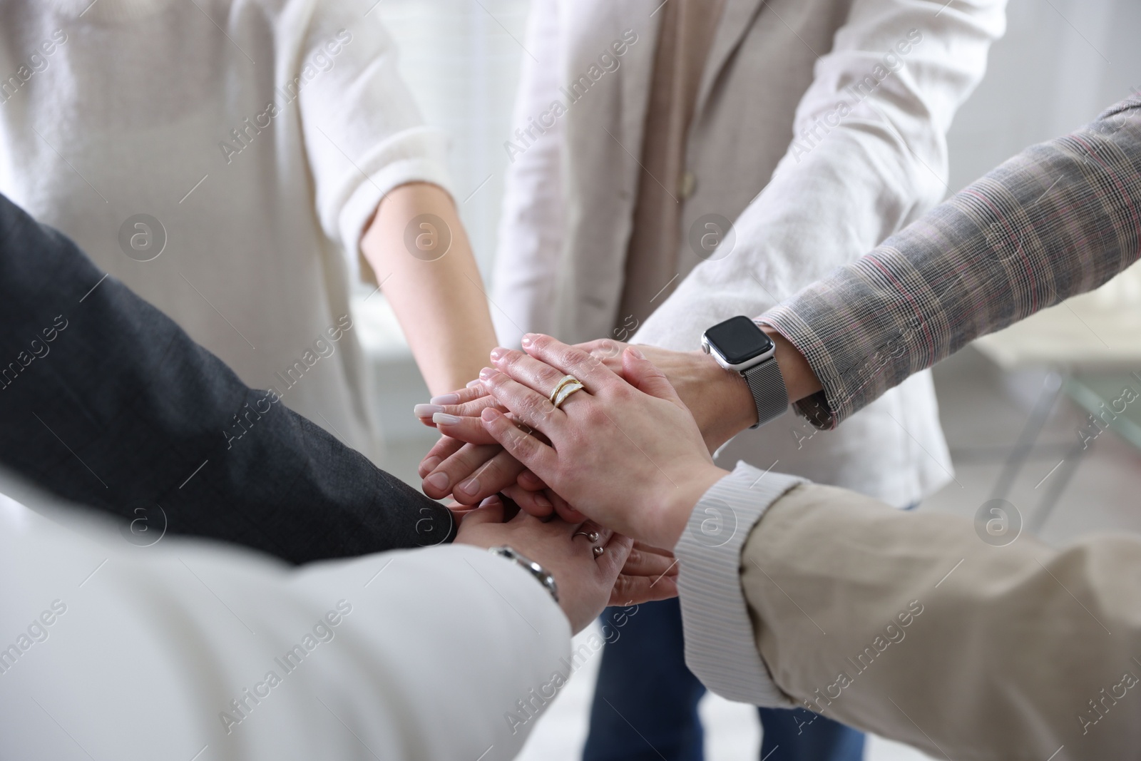 Photo of Unity concept. People holding hands together indoors, closeup