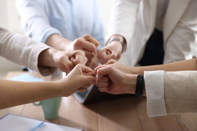 Photo of Unity concept. People holding fists together indoors, closeup