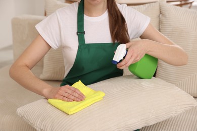 Janitor cleaning sofa with rag at home, closeup