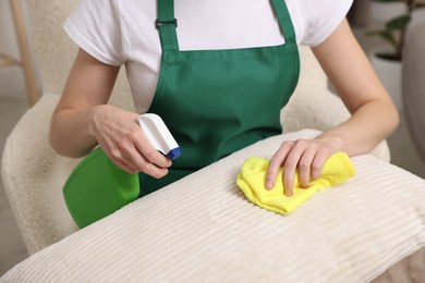 Photo of Janitor cleaning sofa cushion at home, closeup