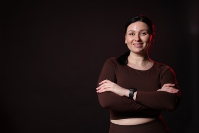 Photo of Plus size woman in gym clothes on black background, space for text