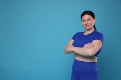 Photo of Plus size woman in gym clothes on light blue background, space for text