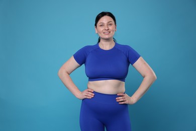 Photo of Plus size woman in gym clothes on light blue background