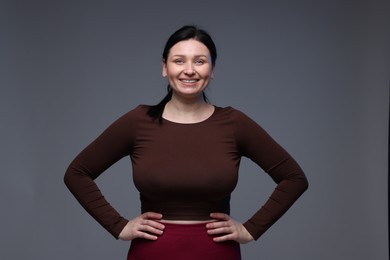 Photo of Plus size woman in gym clothes on grey background