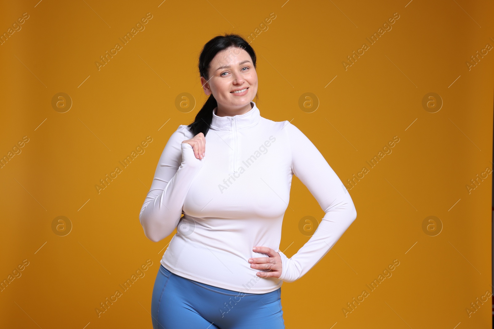 Photo of Plus size woman in gym clothes on orange background