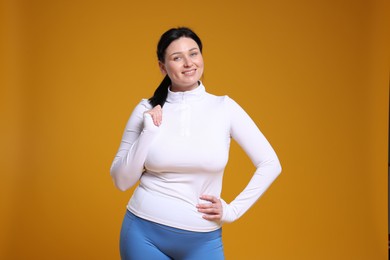 Photo of Plus size woman in gym clothes on orange background