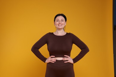 Photo of Plus size woman in gym clothes on orange background