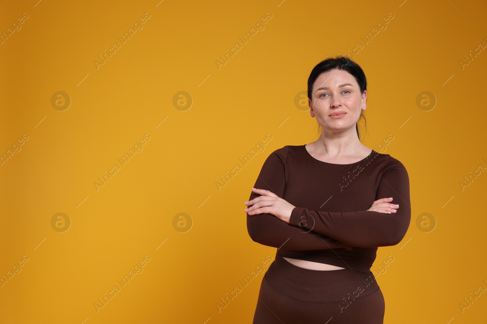 Photo of Plus size woman in gym clothes on orange background, space for text