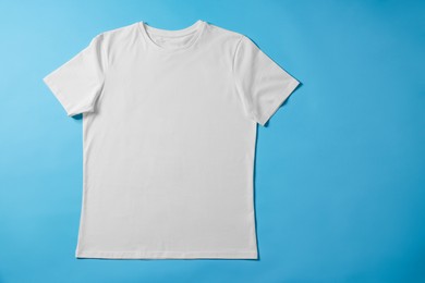 Photo of One blank t-shirt on light blue background, top view. Mockup for design