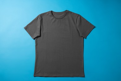 Photo of One blank t-shirt on light blue background, top view. Mockup for design