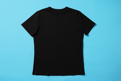 Photo of One blank t-shirt on light blue background, top view. Mockup for design