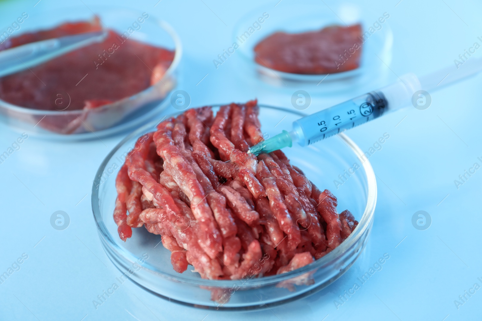 Photo of GMO concept. Minced meat and syringe on table in laboratory, closeup