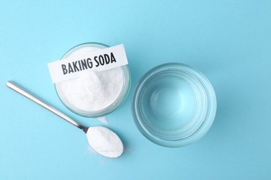 Photo of Glass of water and baking soda on light blue background, top view