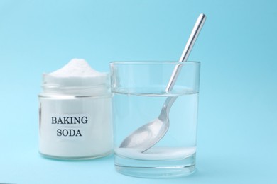 Photo of Glass of water and baking soda on light blue background