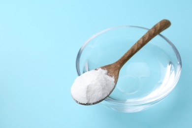 Photo of Glass of water and baking soda on light blue background, closeup