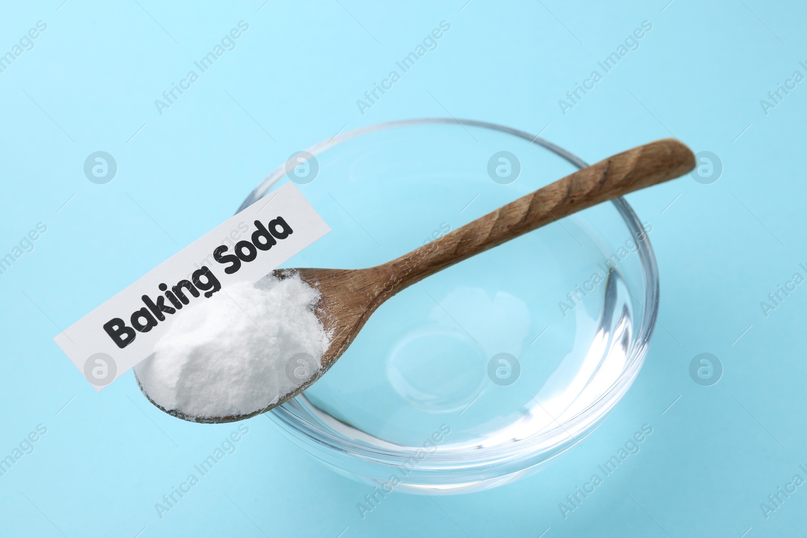 Photo of Glass of water and baking soda on light blue background, closeup