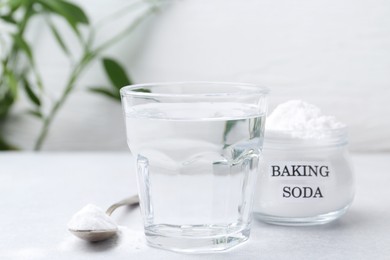 Photo of Glass of water and baking soda on white table, closeup