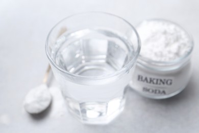 Photo of Glass of water and baking soda on white table, selective focus