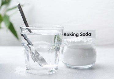 Photo of Glass of water and baking soda on white table, closeup