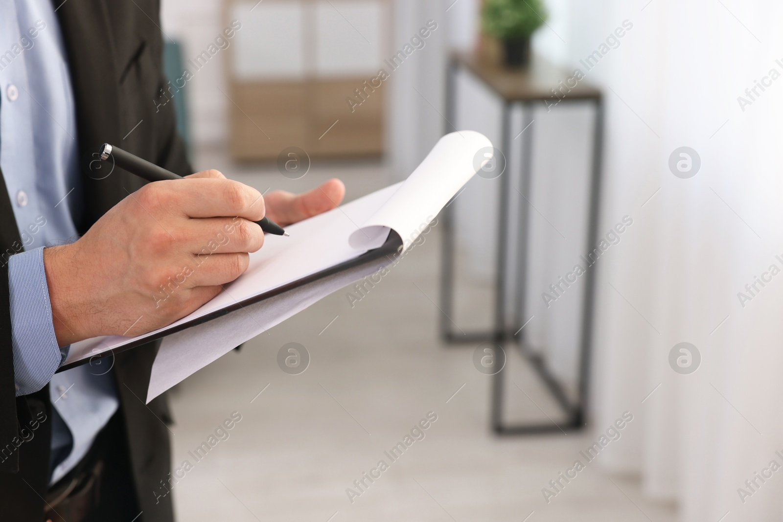 Photo of Real estate appraisal. Inspector with clipboard conducting property valuation at home, closeup. Space for text