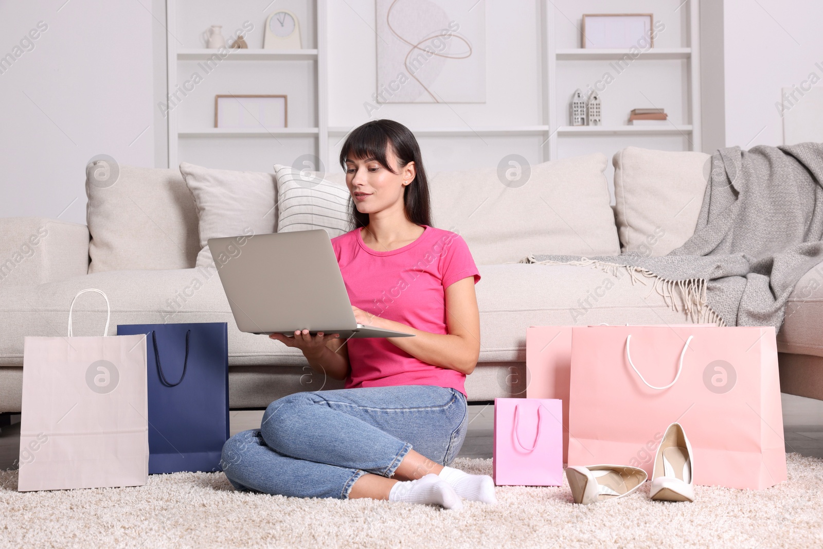 Photo of Internet shopping. Beautiful woman with laptop and colorful bags at home