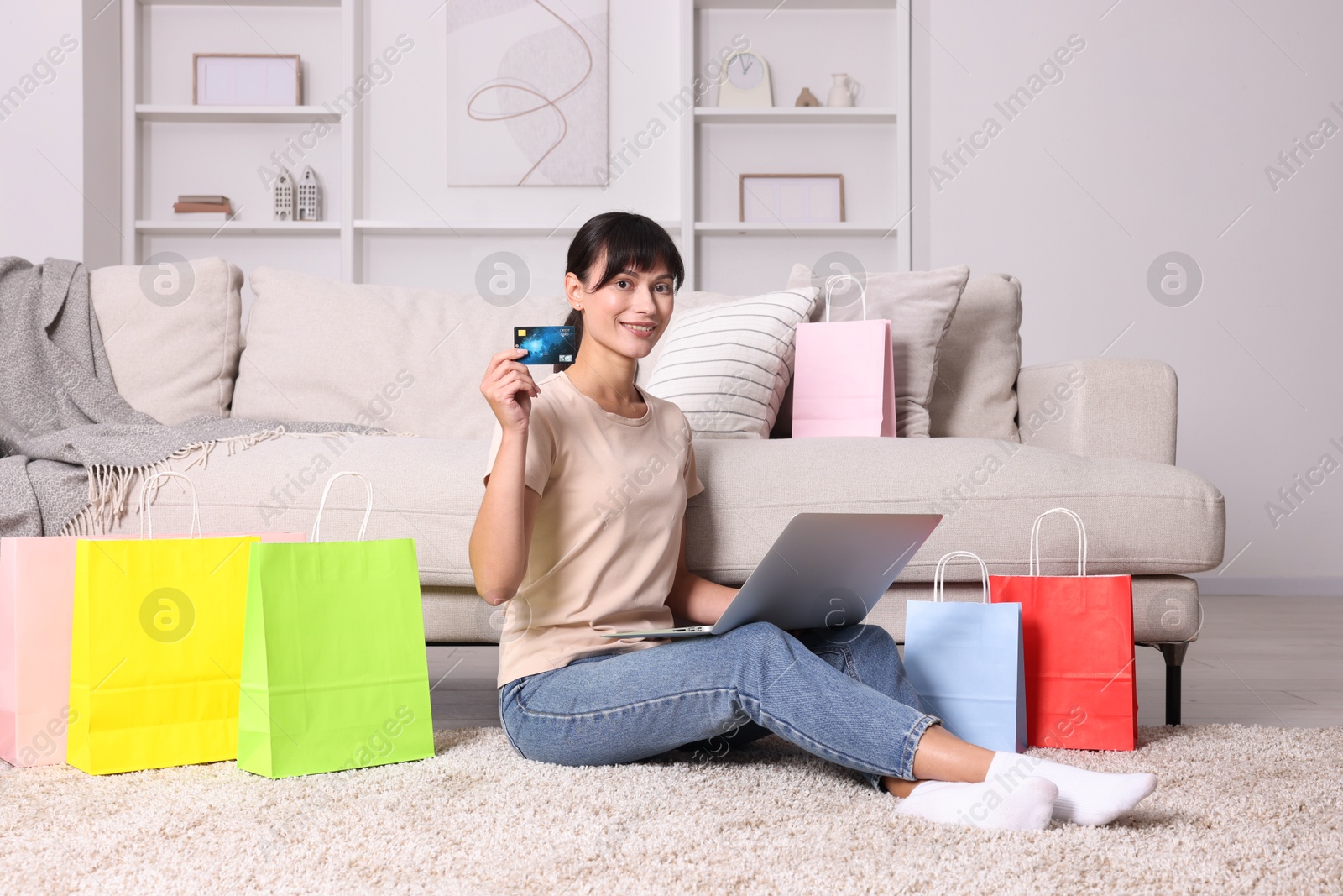 Photo of Internet shopping. Happy woman with credit card, laptop and colorful bags at home