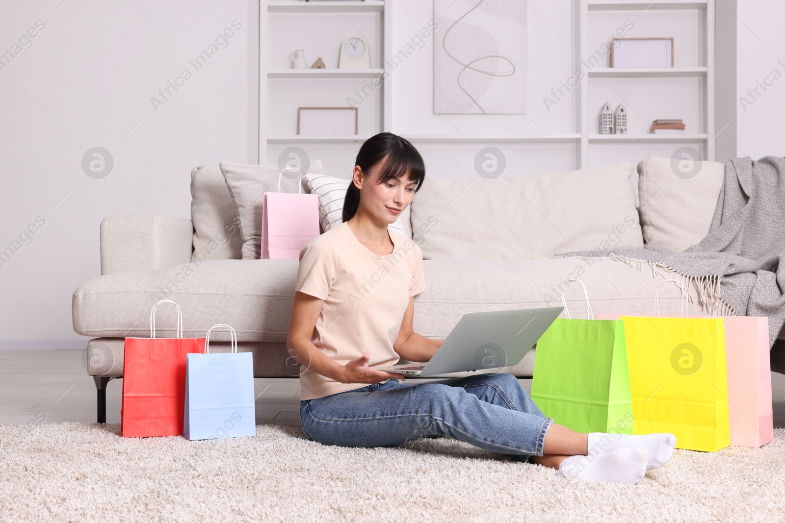 Photo of Internet shopping. Beautiful woman with laptop and colorful bags at home