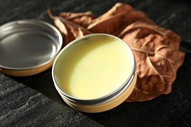 Photo of Natural solid perfume and dry leaf on black table, closeup