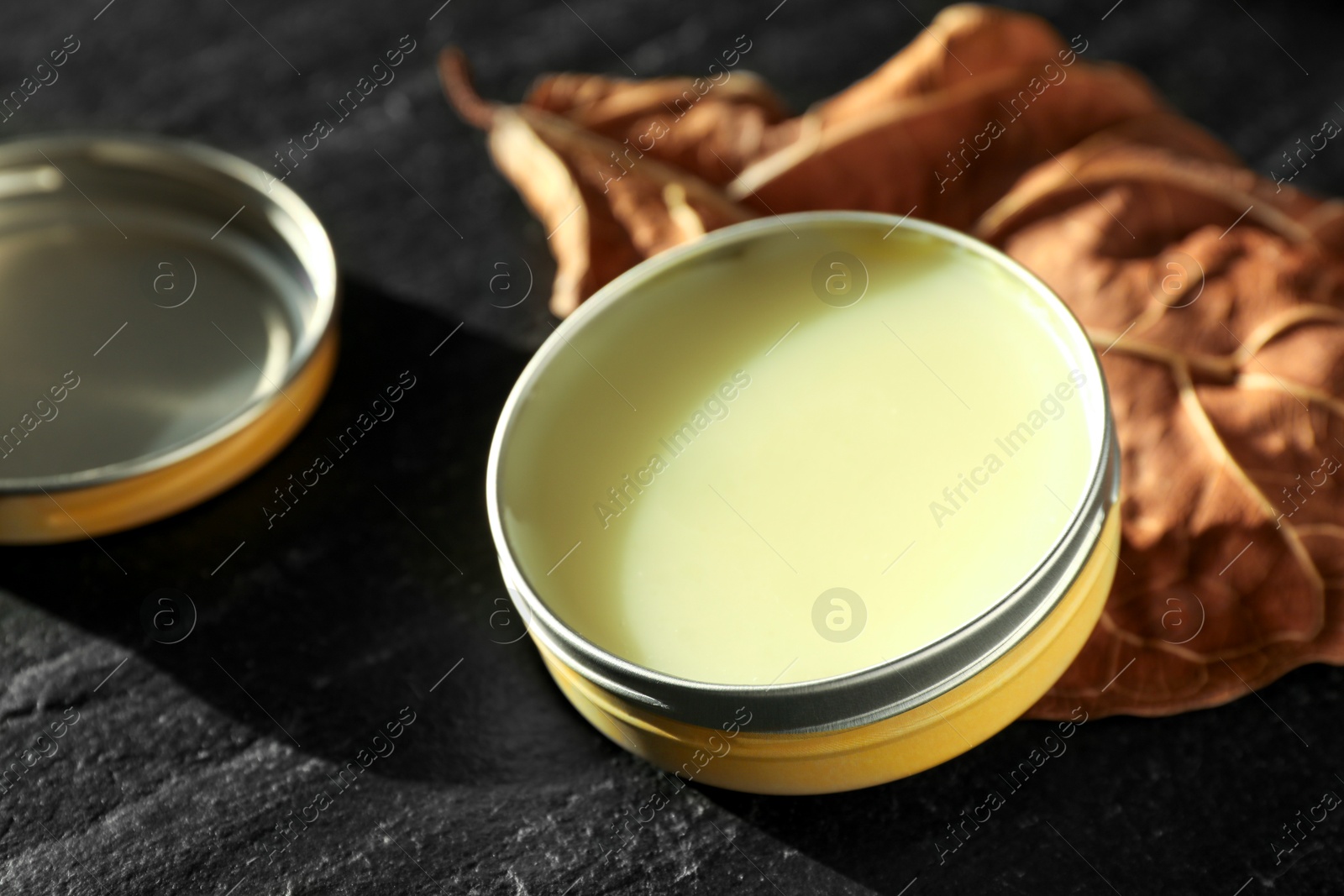 Photo of Natural solid perfume and dry leaf on black table, closeup