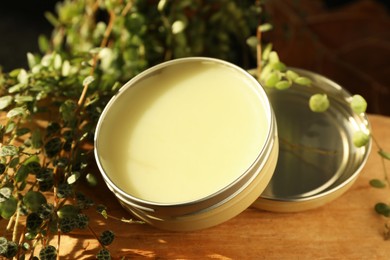 Photo of Natural solid perfume and plant on wood, closeup