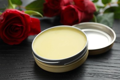 Photo of Natural solid perfume and roses on black wooden table, closeup