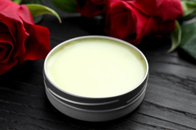 Photo of Natural solid perfume and roses on black wooden table, closeup