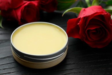 Photo of Natural solid perfume and roses on black wooden table, closeup