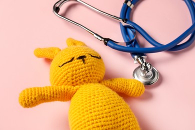 Photo of Pediatrics concept. Toy bunny with stethoscope on pink background