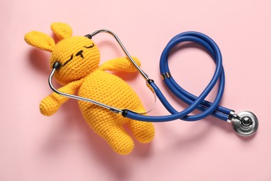 Photo of Pediatrics concept. Toy bunny with stethoscope on pink background