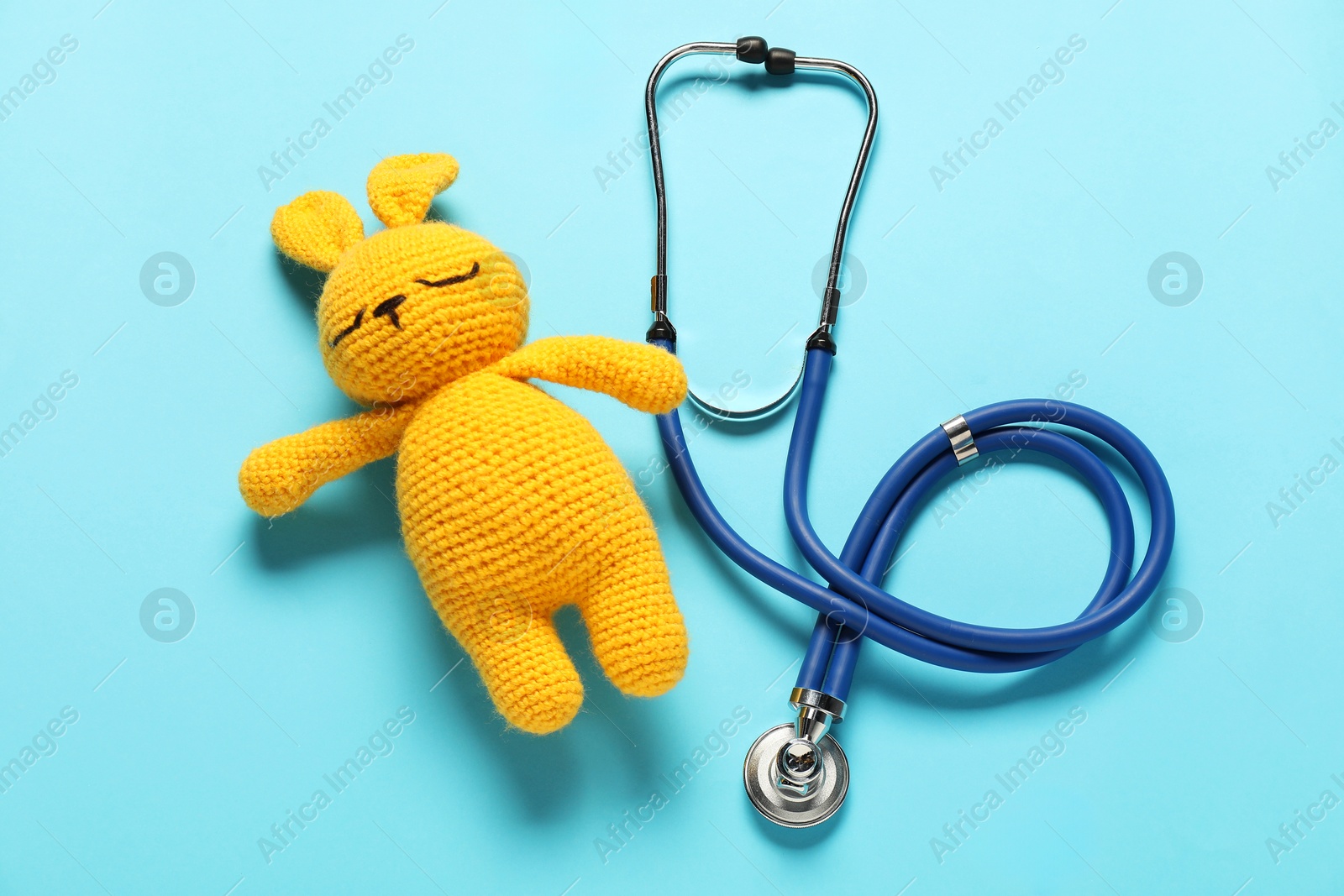 Photo of Pediatrics concept. Toy bunny with stethoscope on light blue background, top view