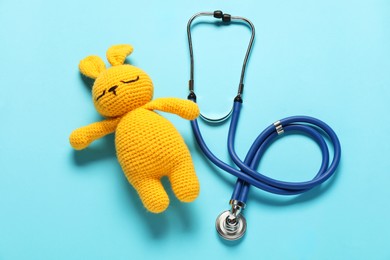 Photo of Pediatrics concept. Toy bunny with stethoscope on light blue background, top view