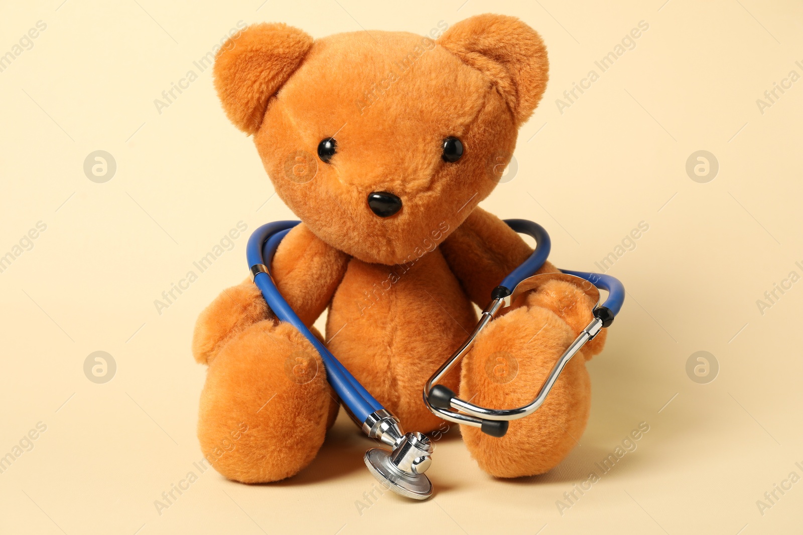 Photo of Pediatrics concept. Teddy bear with stethoscope on beige background