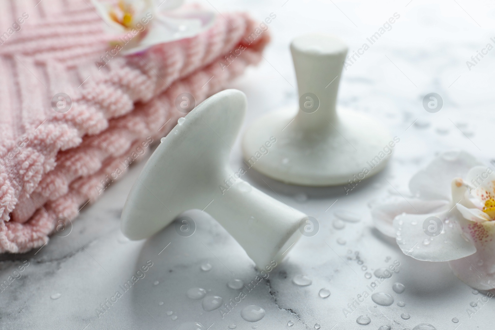 Photo of Wet spa stones, orchid flowers and towel on white marble table, closeup