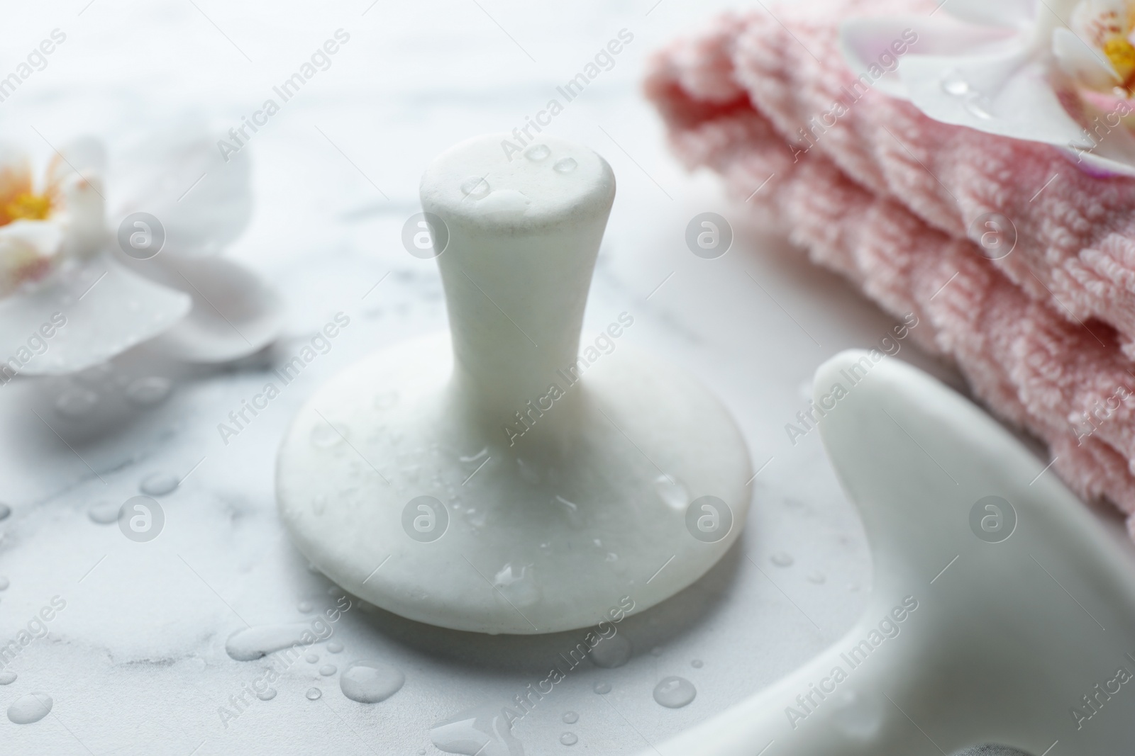 Photo of Wet spa stones, orchid flowers and towel on white marble table, closeup